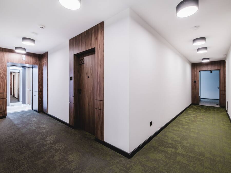 A hallway with wooden paneling, a green carpet, and a door marked with the number 22.