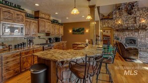 A spacious kitchen with wooden cabinets, a large island, and a stone fireplace.