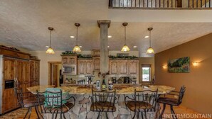 A spacious kitchen with a large island, wooden cabinets, and hanging pendant lights.
