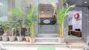 A hotel entrance with a staircase, potted plants, a reception desk, and a fire hose mounted on the wall. - Hotel Airport View (New Delhi)