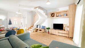 Un salon moderne avec un escalier, un téléviseur à écran plat et un coin repas comprenant des chaises et une table.