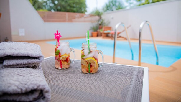 Deux bocaux en verre contenant une boisson, une pile de serviettes et une scène se déroulant au bord de la piscine.