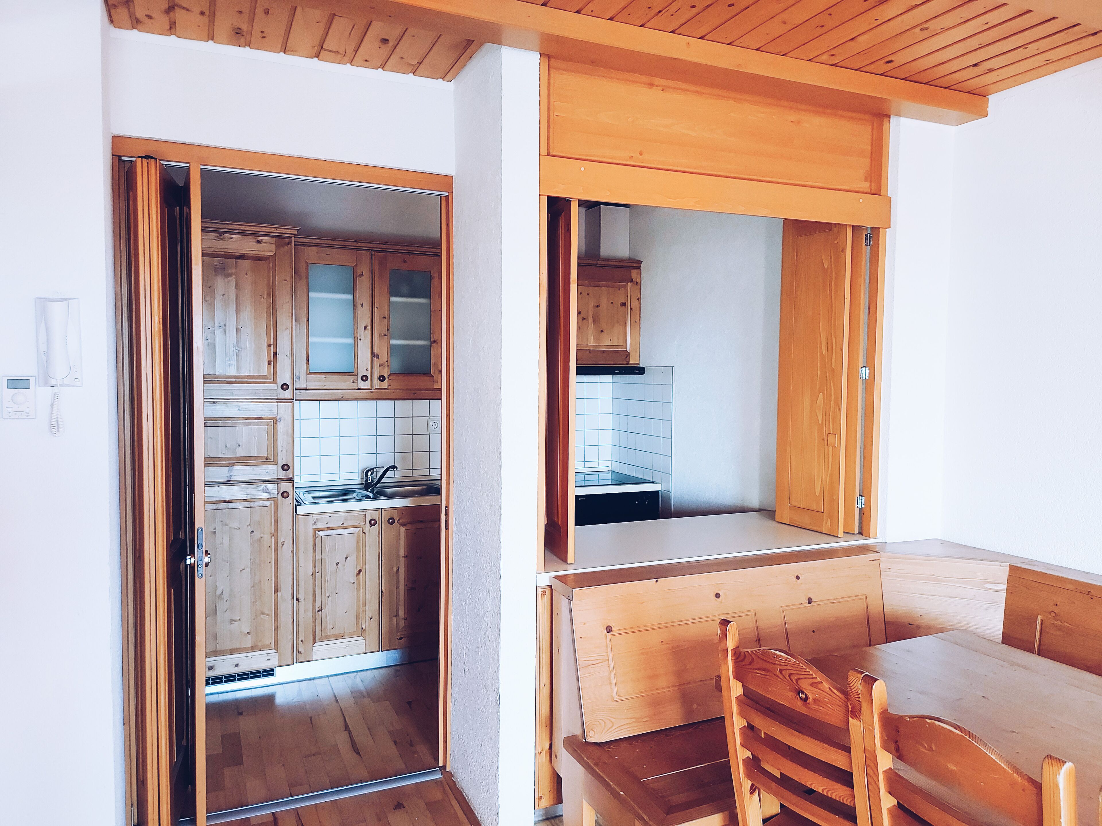 Ein Holzinterieur mit Küchenzeile, Esstisch und einer Bank.