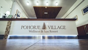 A reception desk at Pohorje Village Wellness & Spa Resort with a wooden ceiling and framed pictures on the wall. - Pohorje Village Wellbeing Resort – Forest Apartments Videc (Maribor)
