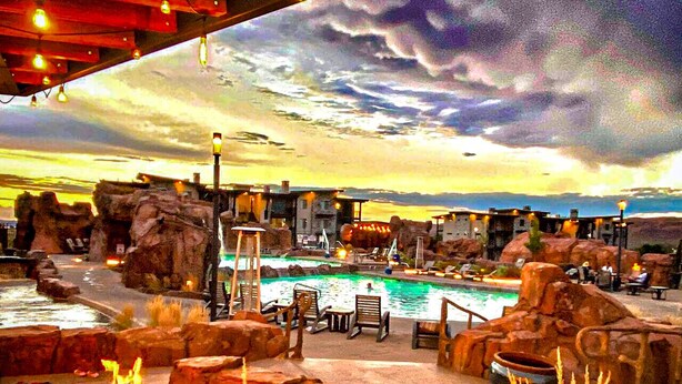A pool area with lounge chairs, a fire pit, and a view of the sky. - Beautiful Brand NEW Luxury Condo @ Sage Creek (Moab)