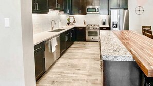 A modern kitchen with dark cabinets, stainless steel appliances, and a wooden island. - Beautiful Brand NEW Luxury Condo @ Sage Creek (Moab)