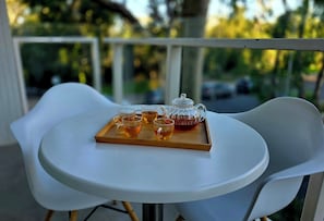 Una mesa redonda con una bandeja de tazas de té y una tetera en un balcón.