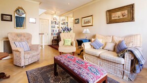 A cozy living room with a patterned rug, a wooden bench, a sofa, and two armchairs.