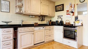 A kitchen with light wooden cabinets, a black countertop, a dishwasher, and an oven.