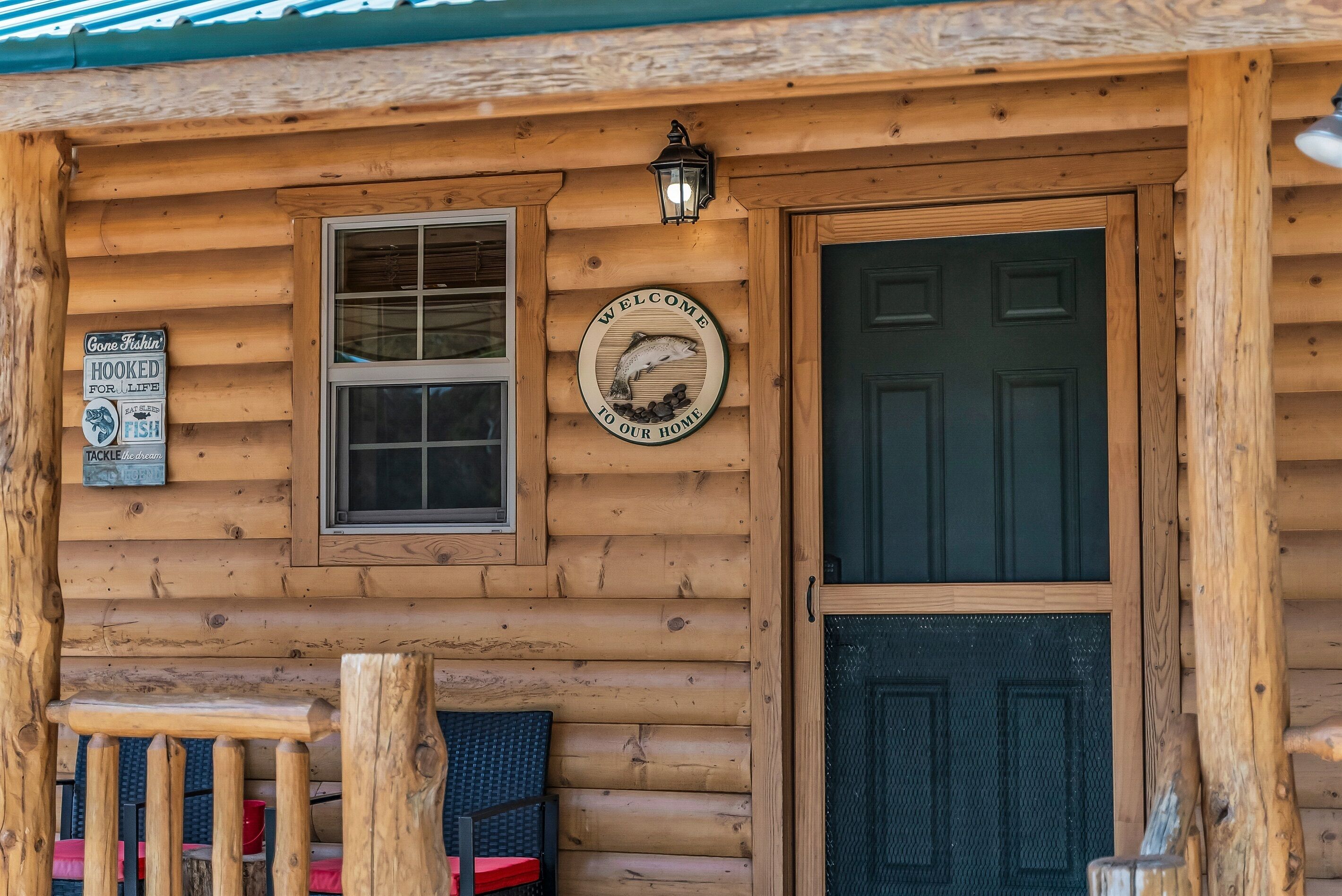 A wooden cabin with a welcome sign, a window, and a door.
