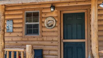 A wooden cabin with a welcome sign, a window, and a door.