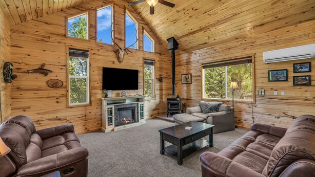 Ein gemütliches Blockhaus-Interieur mit Kamin, Ledersofas, Fernseher und Holzofen.