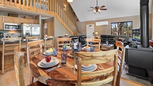 A spacious kitchen with modern appliances, a dining area with a wooden table and chairs, and a cozy living room with a fireplace. - High Country Escape | Forest Border • Fenced Yard (Heber)