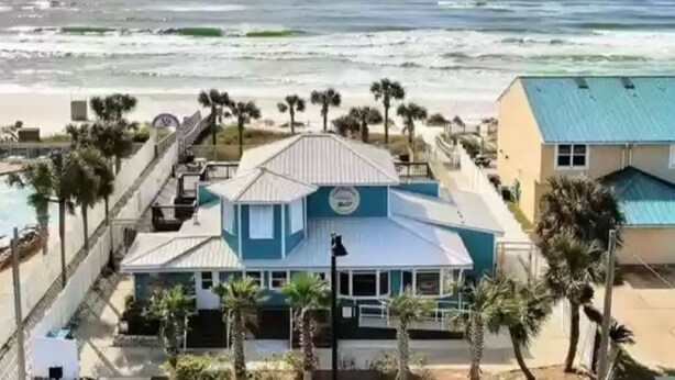 Uma propriedade à beira-mar com uma casa grande, piscina e palmeiras.