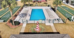 Une piscine avec des chaises longues et un terrain de jeu de palet.