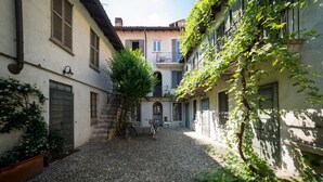 A narrow cobblestone alley with buildings on either side, featuring a staircase, a bicycle, and a tree in the center. - HbHall - Navigli 2 Apartment  (Milan)