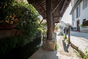 A covered outdoor area with a stone bench, a narrow water channel, and a cobblestone path. - HbHall - Navigli 2 Apartment  (Milan)