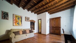A spacious room with a wooden ceiling, a beige sofa, wooden flooring, and a large wooden cabinet. - HbHall - Navigli 2 Apartment  (Milan)