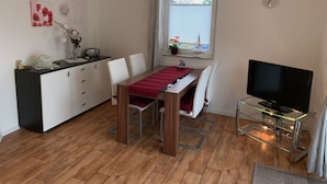 Een knus woongedeelte met een eethoek, kitchenette en televisie.