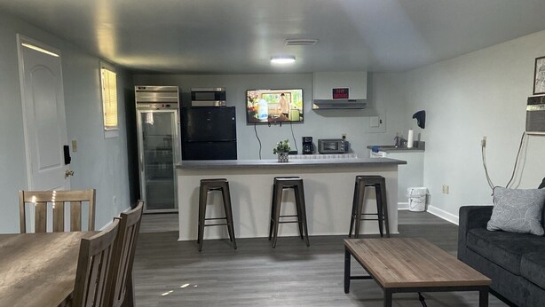 A modern living room with a dining area, a kitchen with a built-in fridge and microwave, and a grey sofa. - Promised Land Countryside Getaway/Campsite  (Bradley)