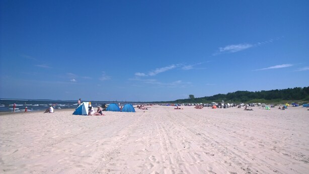 Ein Sandstrand mit Zelten und Menschen.