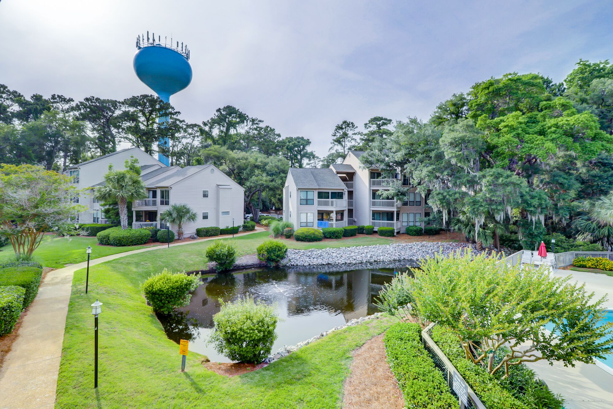 A residential area with two-story houses, a small pond, and a walking path.