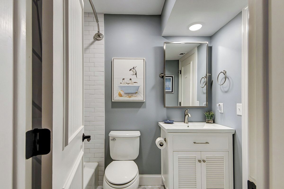 A bathroom with a toilet, sink, and mirror.