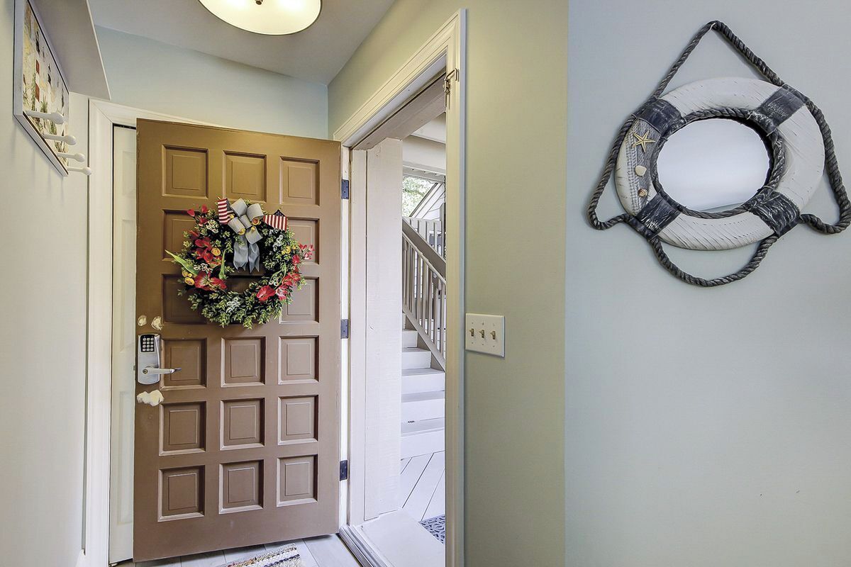 A door with a wreath, a staircase, and a wall-mounted life preserver.
