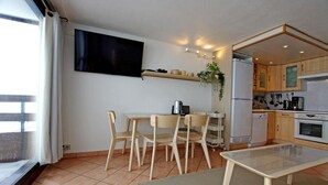 Ein kompakter Wohnbereich mit Essbereich, Küchenzeile und einem an der Wand befestigten Fernseher.