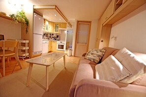 A compact living space with a kitchenette, a dining area, and a sofa with cushions.