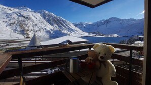Aussicht auf eine verschneite Berglandschaft mit einem See und einem Gebäude in der Ferne.