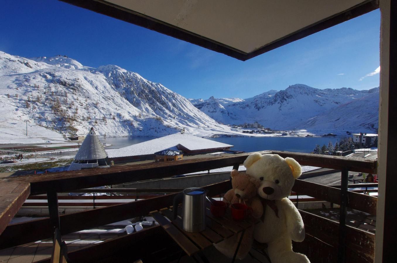 Aussicht auf eine verschneite Berglandschaft mit einem See und einem Gebäude in der Ferne.