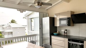 A kitchen with a refrigerator, microwave, oven, and a dining area with a table and chairs. - Éden love! (Collectivité de Saint-Martin)