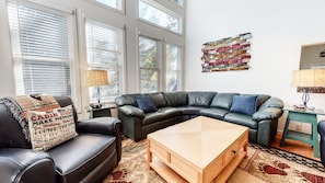 A living room with a leather sectional sofa, a wooden coffee table, and a patterned rug.