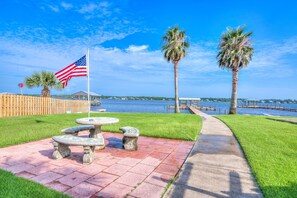 A waterfront patio with a flag, palm trees, and a view of the water.