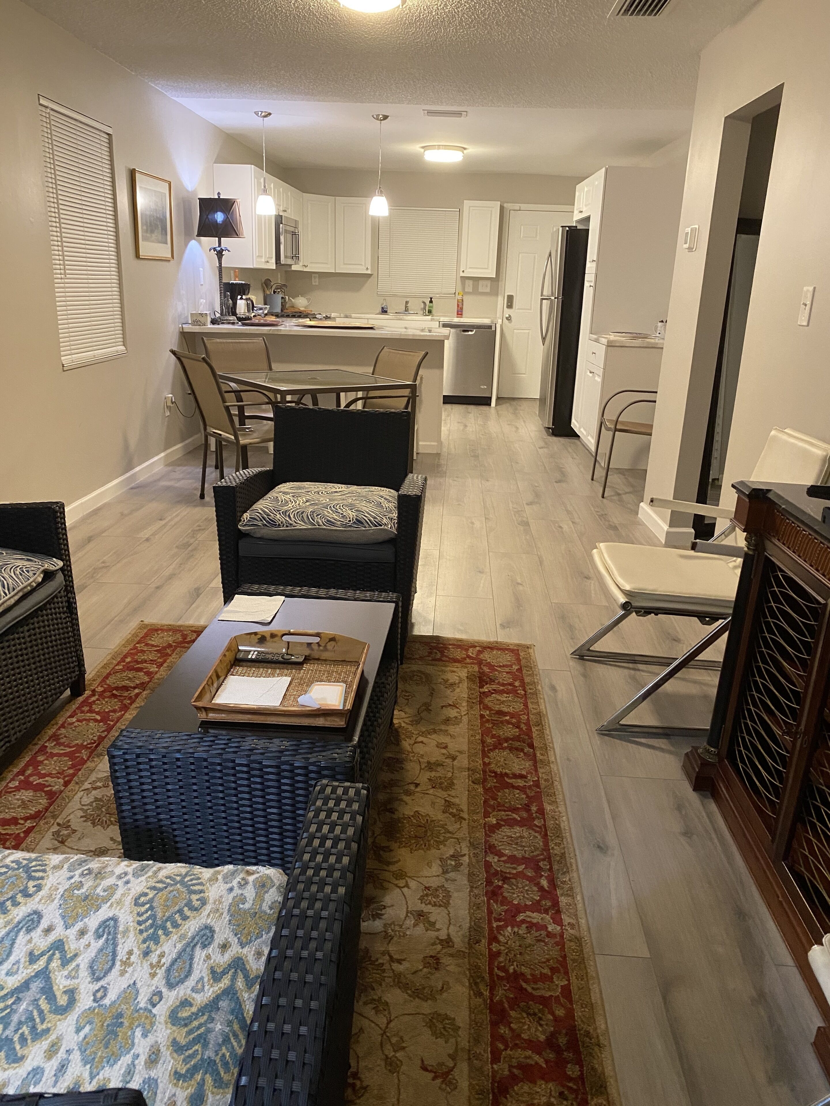 A modern living room with a dining area, kitchen, and a small office space.