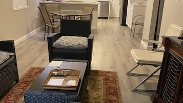 A modern living room with a dining area, kitchen, and a small office space.