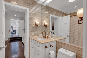 Une salle de bain moderne avec un grand miroir, deux lavabos et des toilettes.