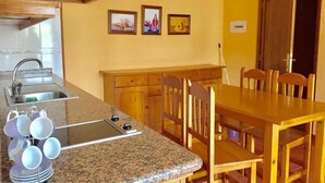 A kitchen with granite countertops, wooden cabinets, a dining table with chairs, and wall-mounted artwork. - Catalina 4 (El Paso)
