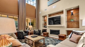 Un salón amplio con chimenea, asientos cómodos y un televisor grande.