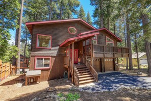 Une cabane en rondins à deux étages, dotée d’une véranda, d’un escalier et d’un garage.