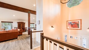 Amplia sala de estar con escalera de madera, un sofá grande y una mesa de comedor.