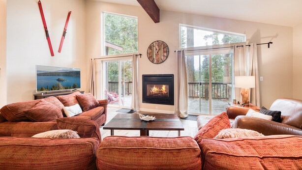 Una sala de estar con chimenea, ventanas amplias y televisor.