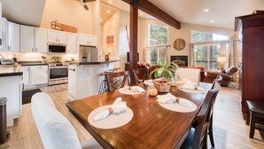 Una cocina amplia con electrodomésticos modernos, un comedor con una mesa de madera dispuesta para cuatro personas y una sala de estar acogedora con chimenea.