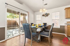A dining area with a table set for four, surrounded by chairs, and a sliding glass door leading to a patio.