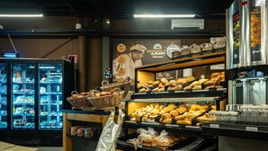 Eine Bäckertheke mit verschiedenen Backwaren und einem Kühlregal im Hintergrund.