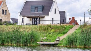 A modern house with a sloped roof, a dock, and a staircase leading up to the entrance. - Premium Water 4p - Two Bedroom Villa, Sleeps 4 (Thorn)
