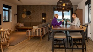 A modern dining area with a wooden table and chairs, a bench, and a large woven light fixture. - Premium Water 4p - Two Bedroom Villa, Sleeps 4 (Thorn)