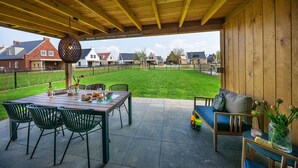 A covered patio area with a wooden table set for dining, surrounded by chairs. - Kids Special 6p - Three Bedroom Villa, Sleeps 6 (Thorn)