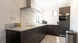 Una cocina moderna con armarios de madera oscura, extractor de acero inoxidable y horno empotrado.